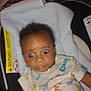 Ezekiel is registered to the contest to win money with this photo: baby, infant, car_seat, blanket, clothing, wide_eyes, expression, surprise, indoor, person, portrait, child, cute, soft, onesie, baby_toys, seat_belt, head, face, young_child