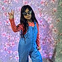 child, girl, sunglasses, blue_overalls, orange_shirt, long_hair, posing, indoor, quilt_background, floral_pattern, fashion, confident, standing, casual_clothing, colorful, portrait, young, cool, expression, floor