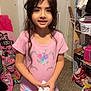 carpet, child, clothing, cute, girl, holding, home, indoor, long_hair, person, pink_shirt, rainbow_skirt, room, shelf, shoes, smiling, standing, towel, toy_box, unicorn