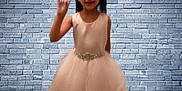 Abbigail joined the competition — help win amazing prizes! child, girl, dress, pink, waving, brick_wall, wooden_floor, indoor, portrait, smiling, formal_wear, young, cute, fashion, posing, person, background, floor, wall, standing