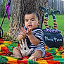 Noah joined the competition — help win amazing prizes! baby, child, striped_clothing, clapping, blanket, tree_trunk, grass, outdoor, halloween, cauldron, witch_legs, broomstick, skeleton_hand, colorful_blanket, green_grass, playful, cute, holiday_decor, costume, seasonal