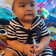 Noah joined the competition — help win amazing prizes! baby, child, striped_clothing, cap, sitting, toys, book, blanket, indoor, hand, face, cute, person, infant, plush, colorful, expression, looking_away, young_child, play