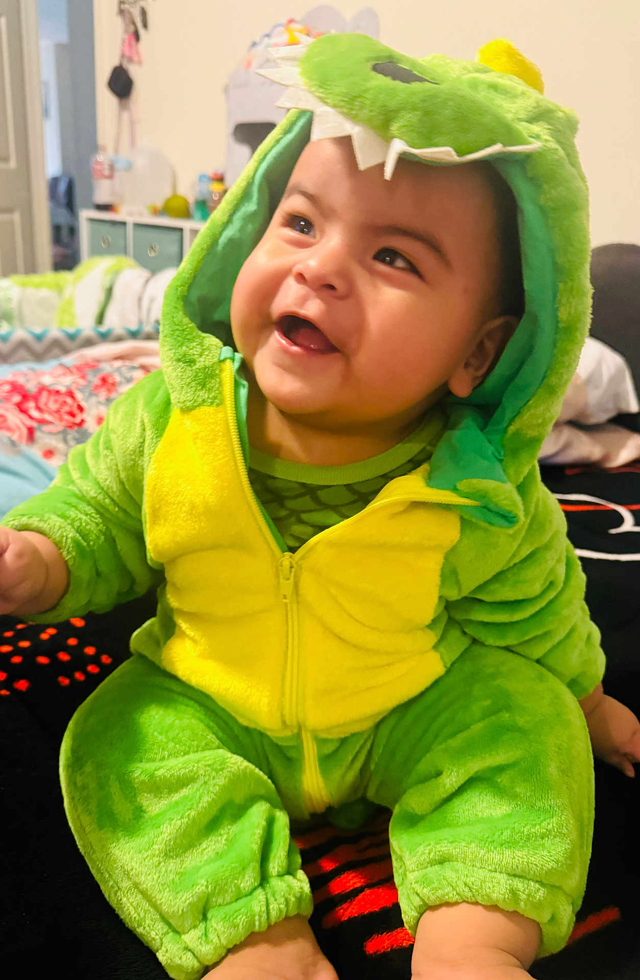 Noah joined the competition — help win amazing prizes! baby, child, costume, dinosaur, green, yellow, smiling, cute, indoors, bedroom, plush, hood, seated, happy, person, infant, apparel, soft, expression, joyful