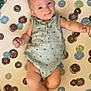 baby, infant, child, onesie, smile, face, legs, arms, skin, pattern, dots, green, blue, brown, white, cute, expression, lying_down, indoor, soft_light