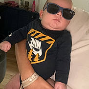 Kassïm participe au concours pour gagner de l'argent avec cette photo : baby, sunglasses, nike, onesie, hand, couch, indoor, person, child, fingernail, casual, relaxed, furniture, home, infant, clothing, sitting, skin, adult, accessory