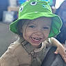child, toddler, smile, green_hat, cute, happy, face, teeth, clothing, overalls, person, indoors, portrait, baby, expression, headwear, casual, young_child, playful, fun