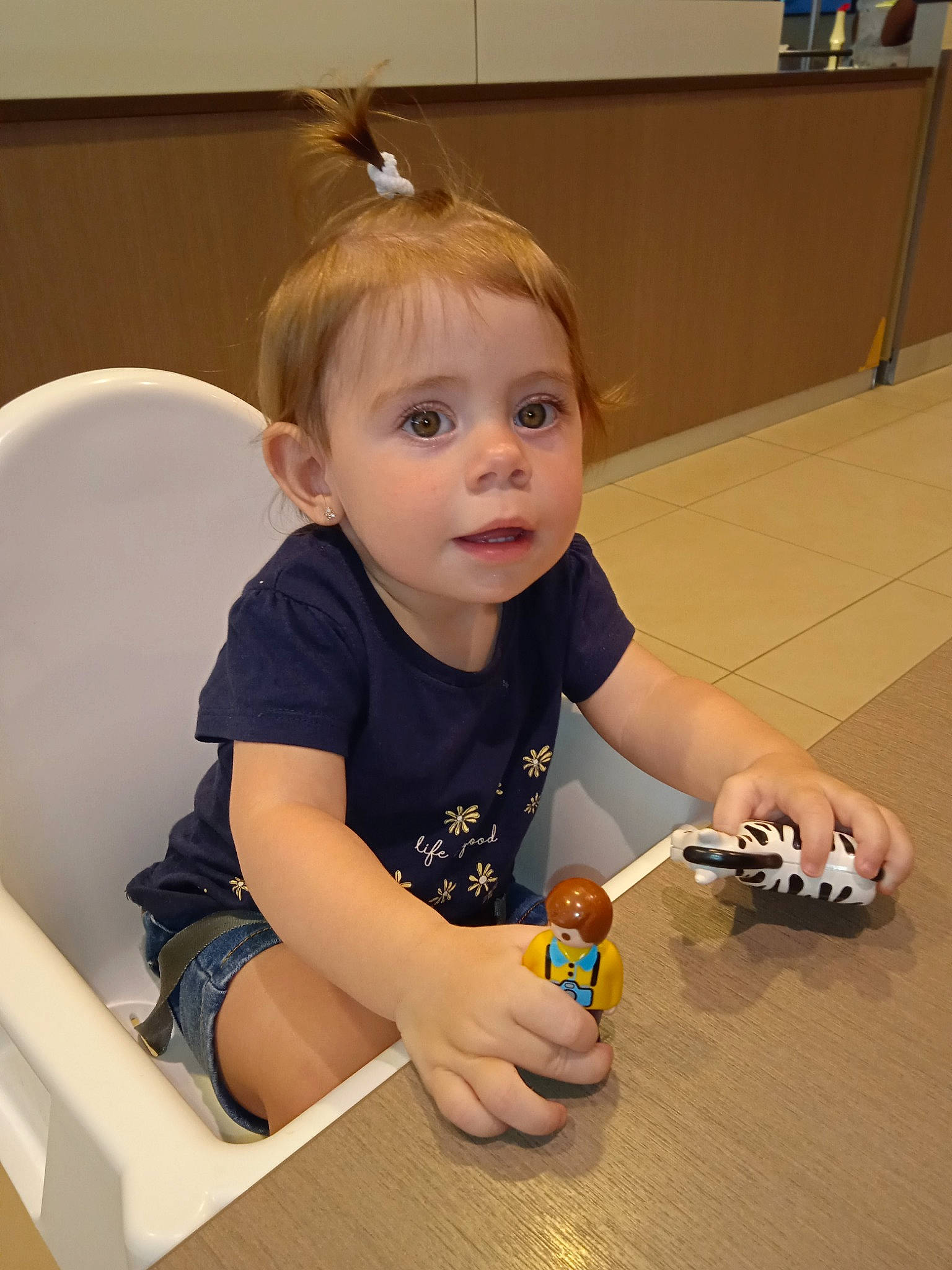 Myléna a rejoint le concours — aidez-le/la à gagner de superbes lots ! baby, baby_playing_with_toys, child, finger, flooring, fun, hand, hardwood, head, nail, person, picture_frame, room, shirt, sitting, t_shirt, thumb, toddler, toy, varnish