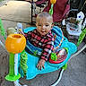 De'Shawn is registered to the contest to win money with this photo: baby, child, infant, jumper, toy, playtime, plaid_shirt, red_shirt, blue_jumper, plastic_toy, indoor, concrete_floor, chair, household_items, smiling, person, young_child, cute, happy, casual_clothing