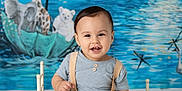 Nicolas Asafe is registered to the contest to win money with this photo: baby, child, smiling, blue_outfit, suspenders, small_bed, fluffy_cushion, white_floor, colorful_backdrop, umbrella_boat, giraffe, elephant, polar_bear, starry_sky, musical_notes, water, mountains, indoor, portrait, happy