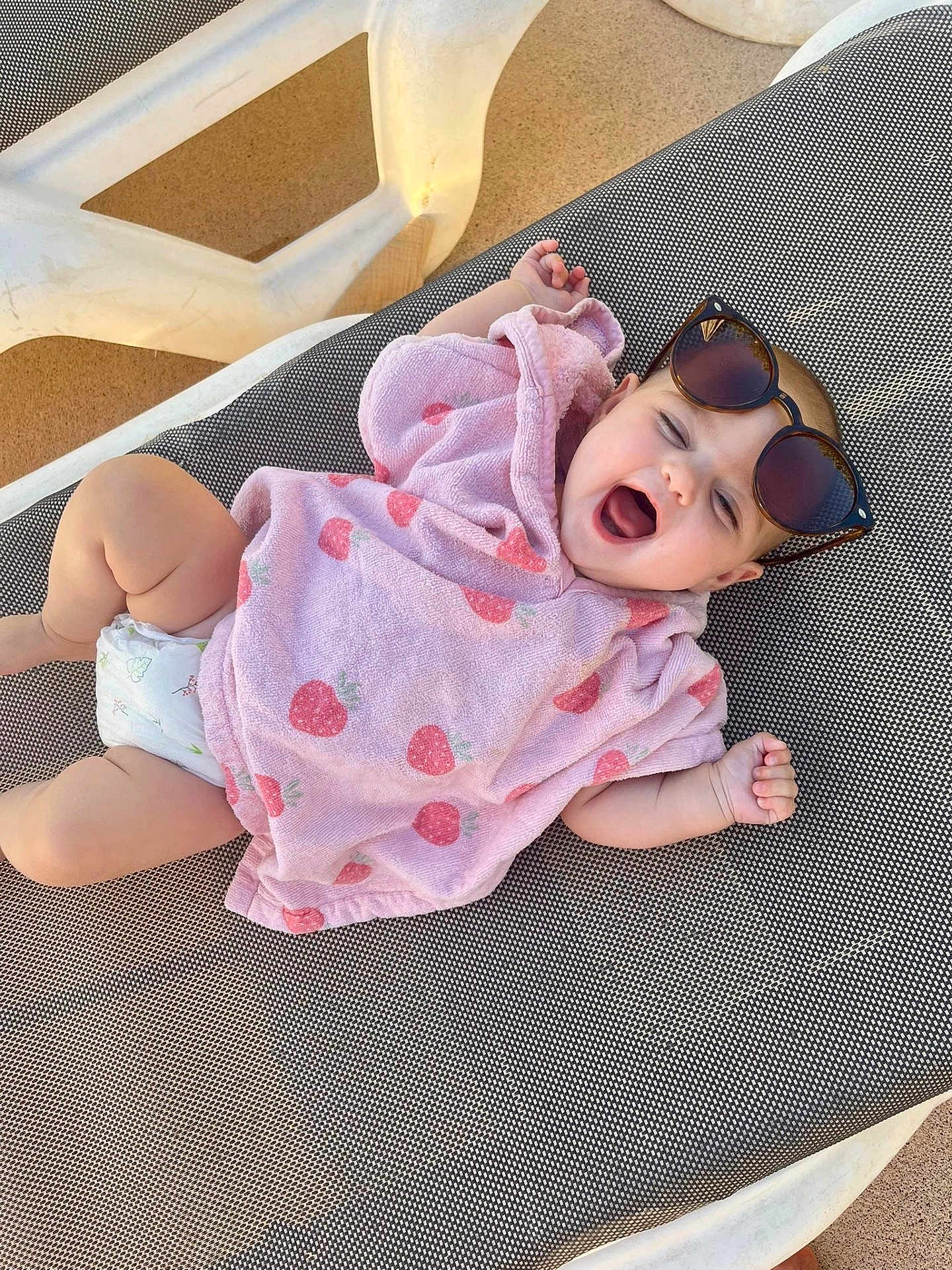 Jade participe au concours pour gagner de l'argent avec cette photo : baby, child, infant, towel, sunglasses, pink, strawberry_pattern, diaper, sun_lounger, outdoor, happy, yawning, relaxing, cute, smiling, skin, person, summer, leisure, daylight