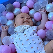 Hadriel participe au concours pour gagner de l'argent avec cette photo : baby, ball_pit, plastic_balls, pink_balls, gray_balls, transparent_balls, dinosaur_pattern, onesie, bib, smiling, happy, child, playtime, indoor, cute, infant, colorful, soft_lighting, closeup, portrait