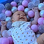 baby, ball_pit, plastic_balls, pink_balls, gray_balls, transparent_balls, dinosaur_pattern, onesie, bib, smiling, happy, child, playtime, indoor, cute, infant, colorful, soft_lighting, closeup, portrait