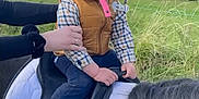 Ilyes participe au concours pour gagner de l'argent avec cette photo : child, baby, helmet, pacifier, horse, saddle, outdoor, grass, trees, person, hand, plaid_shirt, vest, shoes, nature, animal, riding, pony, braided_hair, sky