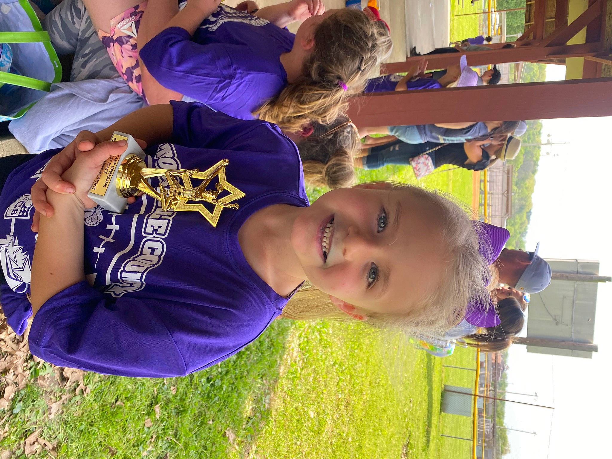 Makenna is registered to the contest to win money with this photo: child, event, fun, grass, happy, hat, headwear, joy, leisure, person, play, purple, recreation, sleeve, smile, t_shirt, toddler, tree, vacation, yellow