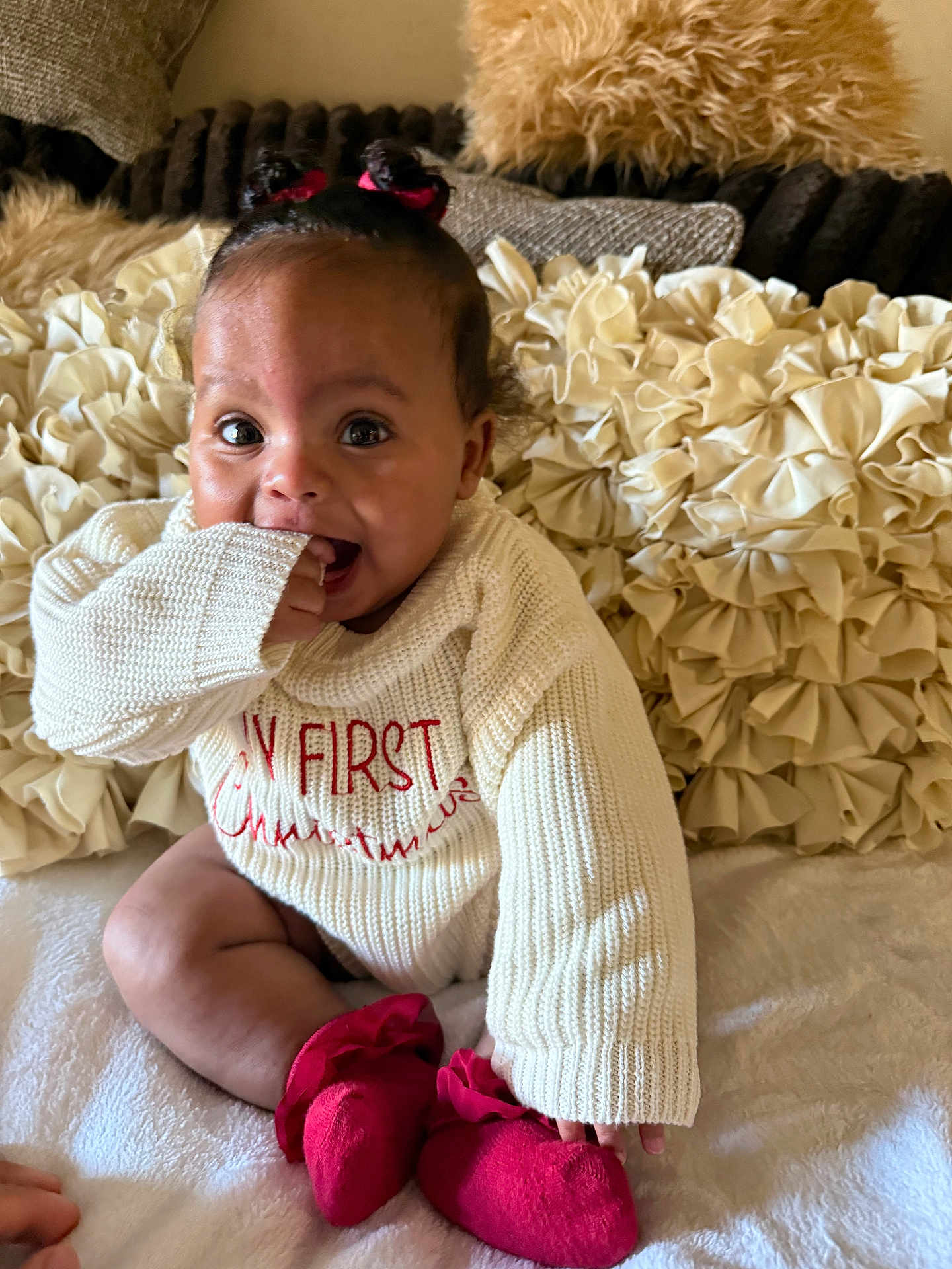 Akira joined the competition — help win amazing prizes! baby, child, infant, sitting, sweater, red_booties, pigtails, cute, cozy, pillows, bed, indoor, smiling, happy, holiday, christmas, knitwear, young_child, portrait, playful