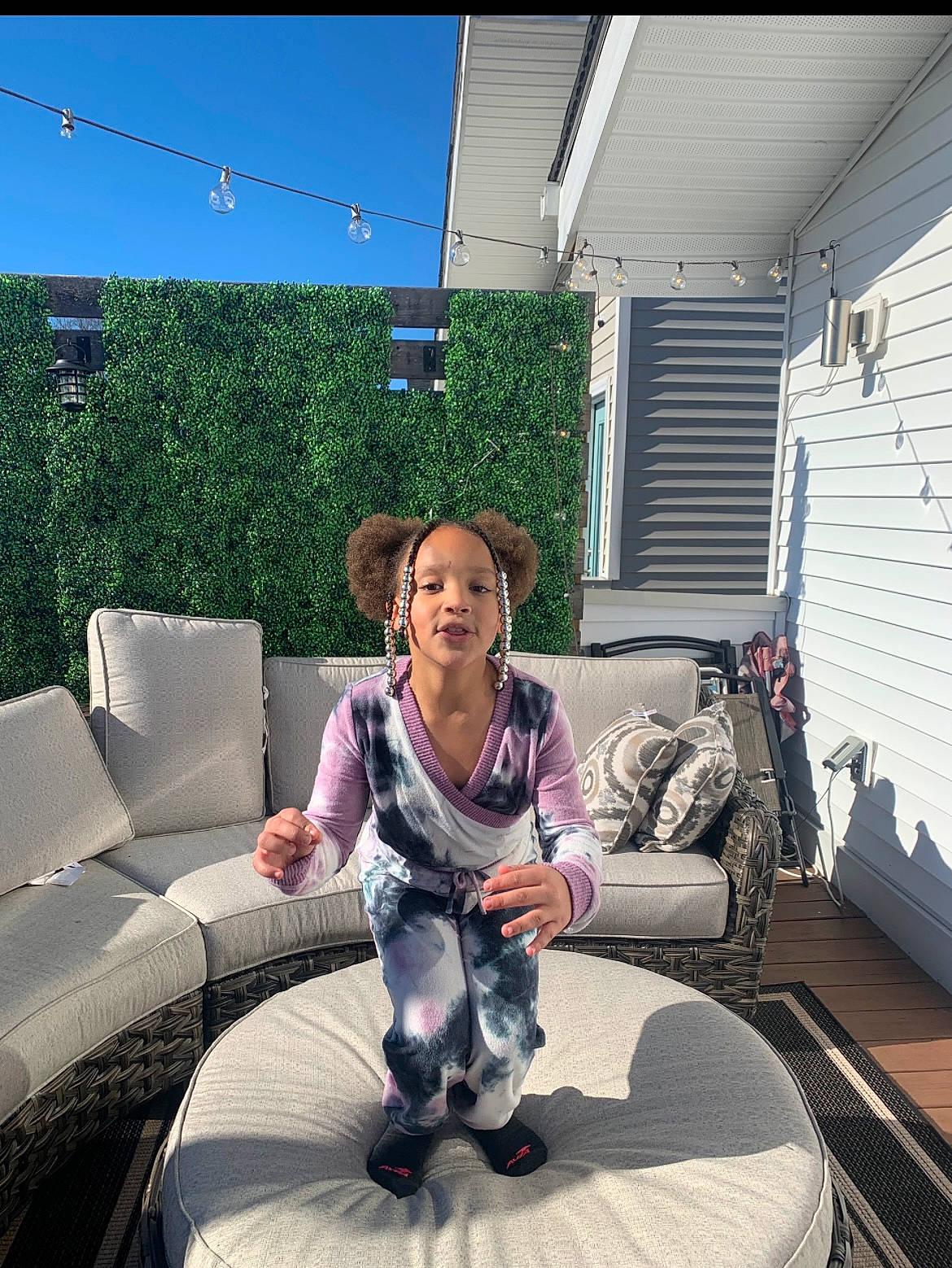 London is registered to the contest to win money with this photo: child, comfort, companion_dog, couch, flooring, fun, furniture, grass, house, lap, leisure, living_room, outdoor_furniture, patio, person, plant, recreation, roof, room, sitting