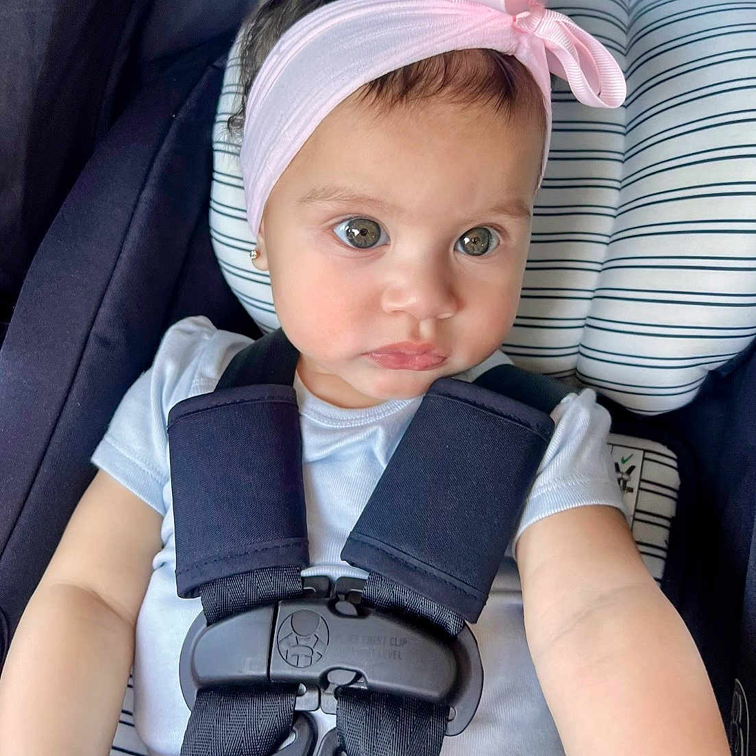Nyelle is registered to the contest to win money with this photo: baby, child, car_seat, headband, pink_bow, safety_harness, white_shirt, infant, seat, cute, portrait, young_child, straps, car_safety, baby_face, expression, indoors, closeup, person, seat_cushion