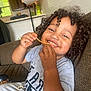 casual, child, clothing, couch, curly_hair, face, food, hair, happy, home, indoor, meal, messy, person, playful, relaxed, sauce, smiling, spaghetti, toddler