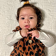 Chloe joined the competition — help win amazing prizes! baby, infant, child, face, eyes, hair, ponytail, expression, clothing, pattern, heart_pattern, button, blanket, texture, portrait, cute, lying_down, hands, white_sleeves, indoor