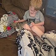 Squeekers joined the competition — help win amazing prizes! blanket, brown_couch, casual_clothing, child, comforter, couch, cozy, dog, furniture, home, indoor, living_room, pet, phone, red_hair, relaxed, seated, small_dog, striped_blanket, technology