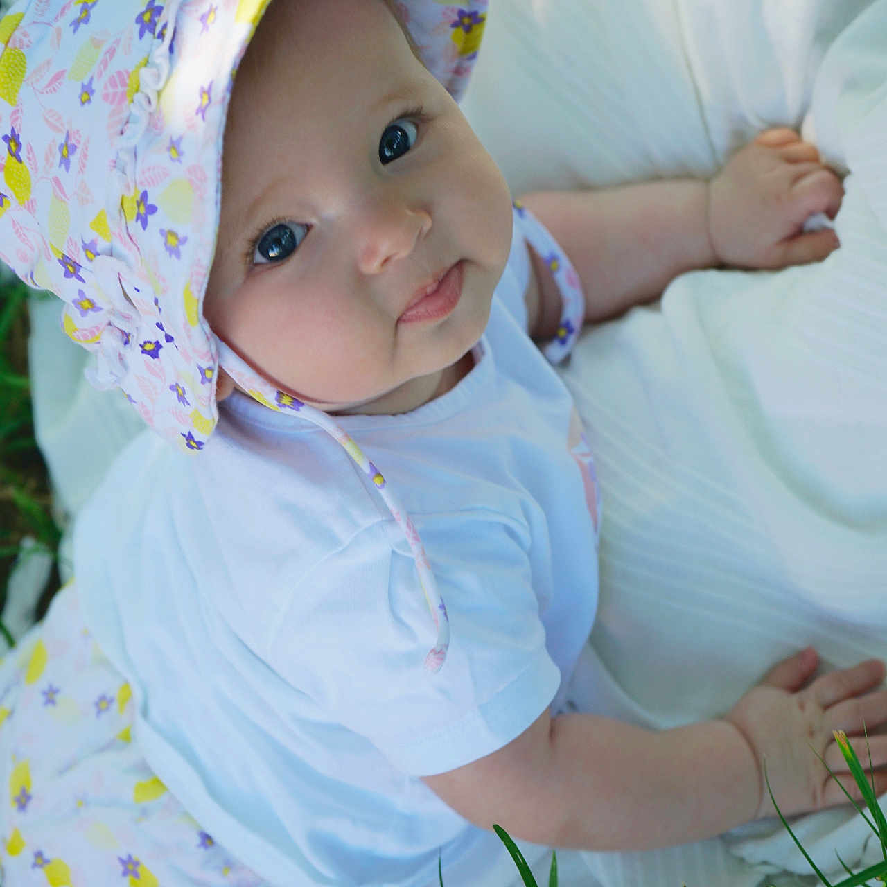 Hisaé a rejoint le concours — aidez-le/la à gagner de superbes lots ! baby, blanket, child, cute, eyes, face, floral, grass, hand, hat, infant, lying, nature, outdoor, person, skin, smile, sunlight, white_clothing, young