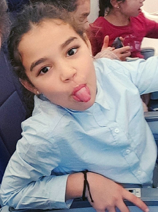 Mouna a rejoint le concours — aidez-le/la à gagner de superbes lots ! cheek, child, eye, eyelash, face, finger, fun, gesture, hair, happy, head, lip, mouth, nose, person, portrait_photography, sitting, skin, t_shirt, thumb