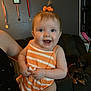 Azelia Lynn is registered to the contest to win money with this photo: baby, child, smiling, orange_bow, striped_dress, person, indoor, living_room, dog, couch, medals, dark_wall, happy, cute, holding, infant, face, hair_bow, pet, home
