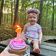 Azelia Lynn is registered to the contest to win money with this photo: toddler, birthday, cupcake, candle, number_one, headband, forest, outdoor, bench, smile, child, dress, diaper, nature, celebration, person, happy, wood, sunlight, hand