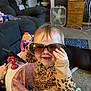 Azelia Lynn is registered to the contest to win money with this photo: baby, sunglasses, leopard_print, walker, pink, smile, happy, child, indoor, toy, living_room, carpet, furniture, couch, cute, person, clothing, funny, head, hand