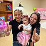 child, birthday, party, celebration, girl, tutu, tiara, smile, happy, indoor, gift, banner, jeans, black_shirt, pink_socks, friends, family, fun, pointing, young