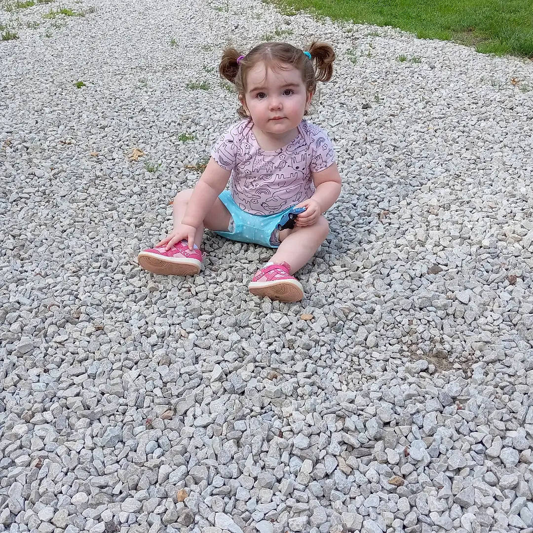 Azaria is registered to the contest to win money with this photo: asphalt, baby_toddler_clothing, flooring, foot, fun, grass, human_leg, landscape, leg, leisure, people_in_nature, person, recreation, road, road_surface, sidewalk, sitting, sneakers, soil, toddler