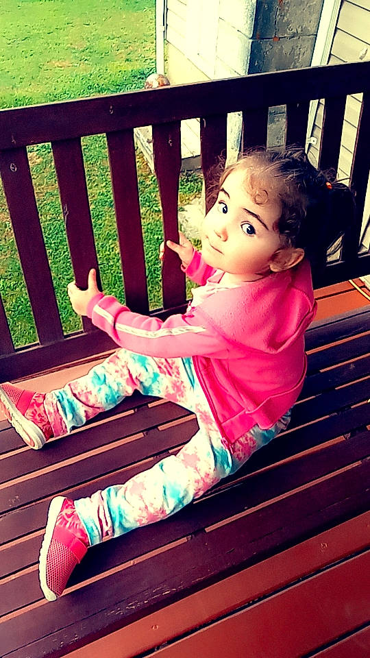 Azaria is registered to the contest to win money with this photo: baby_toddler_clothing, child, comfort, fun, grass, hand, happy, human_body, human_leg, leisure, line, magenta, outdoor_furniture, people_in_nature, person, pink, purple, sitting, tints_and_shades, toddler