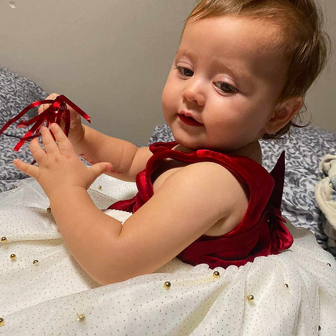 Natalie is registered to the contest to win money with this photo: baby, bed, bedroom, blanket, bodypart, clothing, dress, face, finger, furniture, hand, head, indoors, openingpresent, person, photography, portrait, quilt, room, sitting