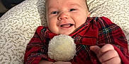 Levi joined the competition — help win amazing prizes! baby, smiling, infant, red_clothing, plaid, pom_pom, cushion, hand, face, indoor, furniture, table, baby_monitor, foot, patterned_fabric, happy, cozy, person, portrait, child