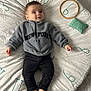 Diogo a rejoint le concours — aidez-le/la à gagner de superbes lots ! baby, barefoot, black_pants, child, clothing, curious_expression, cute, face, grey_pullover, indoors, infant, lying_down, natural_light, numbers, person, pillows, smiling, soft_textures, white_mat, wooden_ring