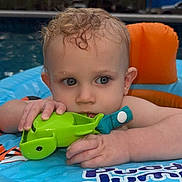 Liam joined the competition — help win amazing prizes! toddler, child, baby, pool, water, inflatable, toy, green_toy, blue, orange, curly_hair, wet_hair, outdoor, summer, play, float, face, hands, expression, evening