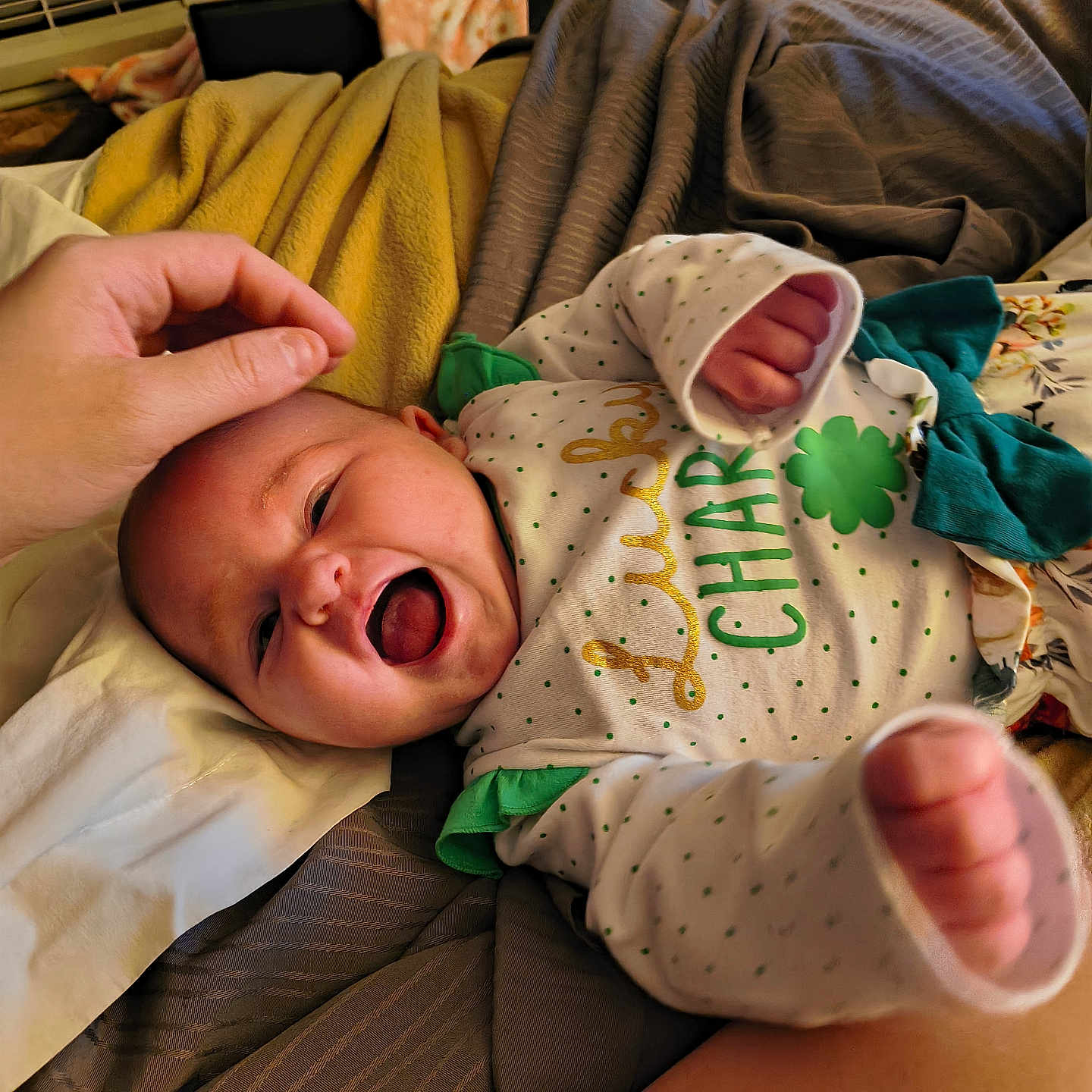 Eliana joined the competition — help win amazing prizes! baby, infant, smile, laugh, hand, bed, blanket, clothing, person, face, cute, joy, warm_light, cozy, sleepwear, green, white, pattern, celebration, happy