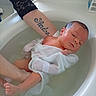 arm, baby, bath, bathtub, care, child, cloth, fresh, gentle, indoors, infant, newborn, parent, person, relaxing, resting, skin, supporting_hand, tattoo, water