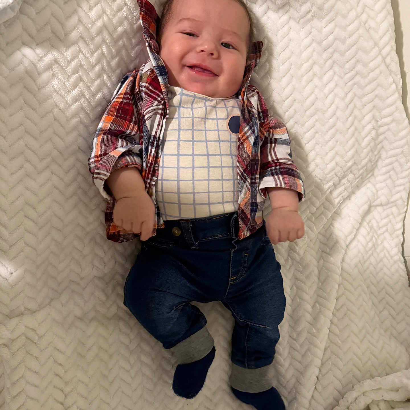 Ethan Mateo is registered to the contest to win money with this photo: baby, blanket, child, clothing, cozy, cute, face, fashion, feet, hands, happy, indoor, infant, jeans, lying_down, plaid_shirt, portrait, smiling, socks, soft_texture