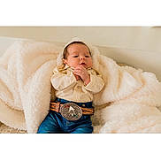 Ethan Mateo joined the competition — help win amazing prizes! baby, blanket, clothing, jeans, belt, belt_buckle, infant, person, cute, indoor, soft_texture, portrait, hands, face, young_child, warm, comfortable, casual, resting, newborn