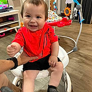 Ethan Mateo joined the competition — help win amazing prizes! baby, child, smile, red_shirt, walker, indoor, hand, toy, floor, person, furniture, television, activity_center, happy, clothing, shorts, socks, living_room, wood_floor, home