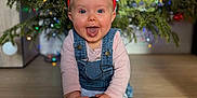 Capucine participe au concours pour gagner de l'argent avec cette photo : baby, blurred_background, celebration, child, christmas_tree, cute, denim_overalls, festive, floor, happy, holiday, indoor, ornament, pink_shirt, red_ball, reindeer_antlers, seasonal, smiling, socks, winter