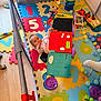 baby, baby_girl, baby_toys, child, child_playing, colorful, colorful_mat, crawling, curious, floor, indoor, infant, number_puzzle, plastic_toys, play_area, playpen, puzzle_mat, soft_mat, toys, wooden_floor