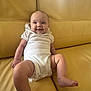 baby, infant, smile, white_onesie, yellow_couch, leather, sitting, happy, cute, child, indoor, portrait, person, skin, young, relaxed, comfortable, small, funny, cozy