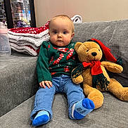 Capucine participe au concours pour gagner de l'argent avec cette photo : baby, blanket, blue_eyes, bottle, child, couch, cute, decor, face, furniture, holiday_theme, indoor, jeans, person, plush_toy, sitting, socks, sweater, teddy_bear, toy