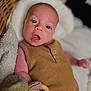 baby, infant, face, eyes, mouth, hand, clothing, brown, knitted_toy, wooden_ring, blanket, soft, basket, indoor, portrait, cute, child, young, skin, expression