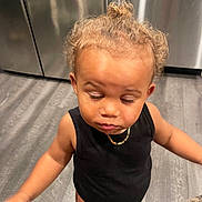 Kyngstyn joined the competition — help win amazing prizes! black_onesie, child, closed_eyes, curly_bun, curly_hair, curly_hair_bun, cute, domestic_animal, floor, flooring, gold_chain, gray_tabby_cat, home, indoor, kitchen_floor, person, pet, standing, toddler, young_child