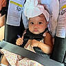 baby, infant, child, car_seat, safety_harness, seatbelt, bow_headband, floral_dress, toy, sitting, portrait, face, eyes, serious_expression, vehicle, automobile, interior, travel, warning_label,  안전