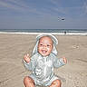 Tru is registered to the contest to win money with this photo: baby, beach, sand, ocean, sky, sunhat, child, smiling, happy, waves, water, outdoor, vacation, summer, barefoot, person, clothing, sitting, sunny, nature