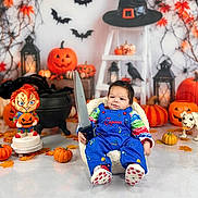 Noa joined the competition — help win amazing prizes! baby, infant, child, portrait, halloween, pumpkins, autumn, costume, blue_overalls, toy_sword, sword, chucky_doll, witch_hat, bats, lantern, skeleton_dog, spooky, decorations, seated, indoors